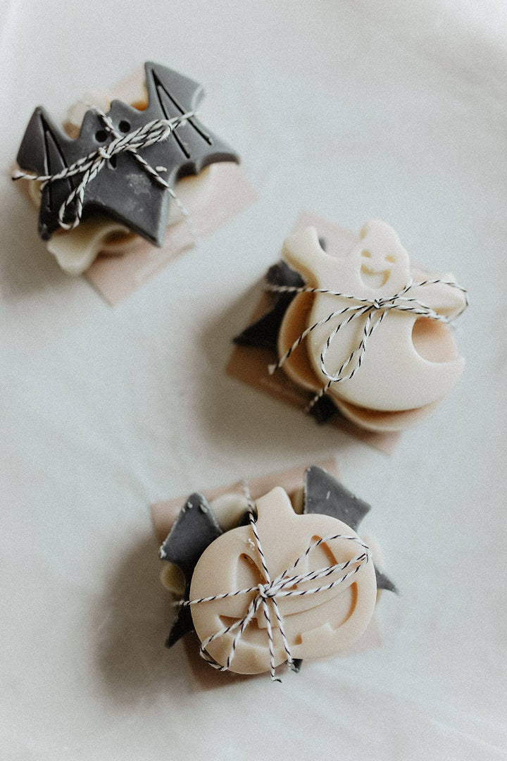 Three small soap bars shaped like ghosts and bats on a white background