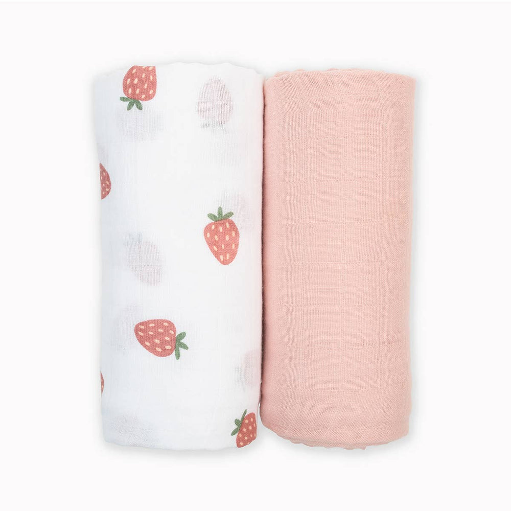 Two Lulujo Baby cotton swaddle blankets, one with strawberry pattern and one with ballet slipper design, laid flat on a white surface.