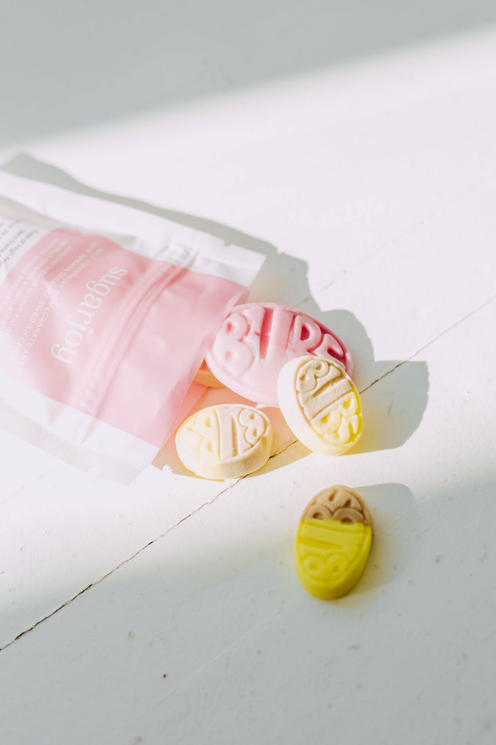 Pink and yellow bath bombs on a white surface with soft shadows