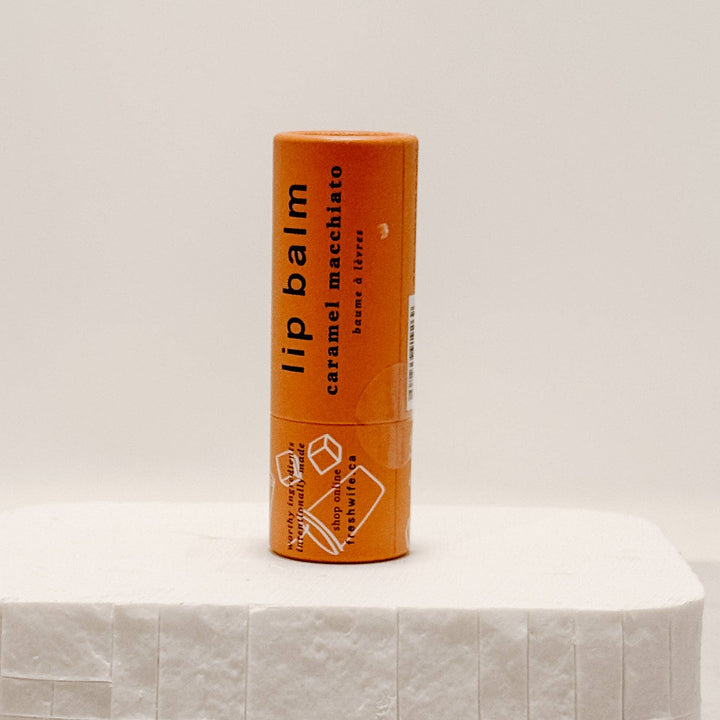Lip balm container with 'caramel macchiato' flavor on a light background