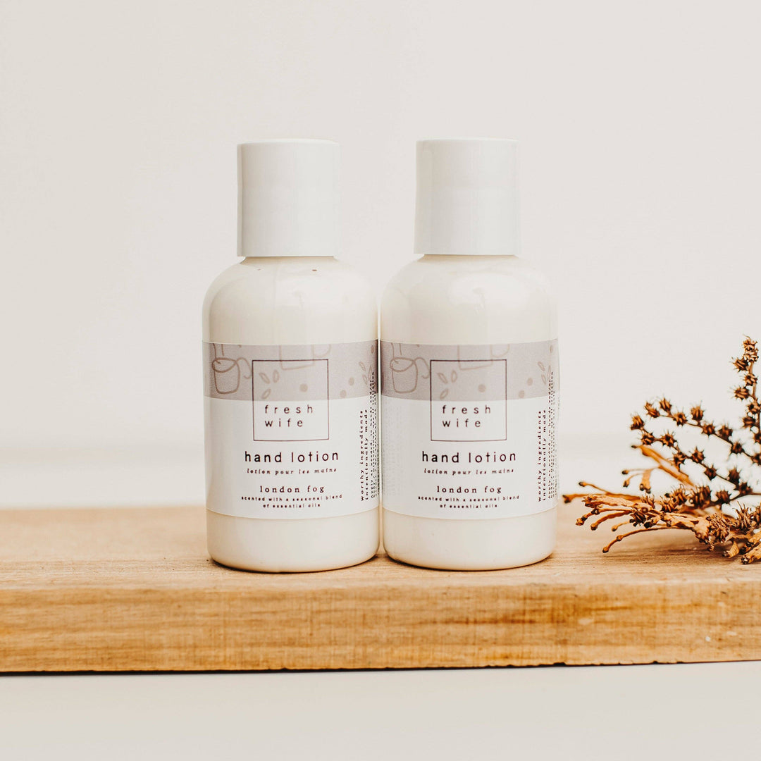 Two bottles of fresh wife hand lotion on a wooden shelf with a minimal background