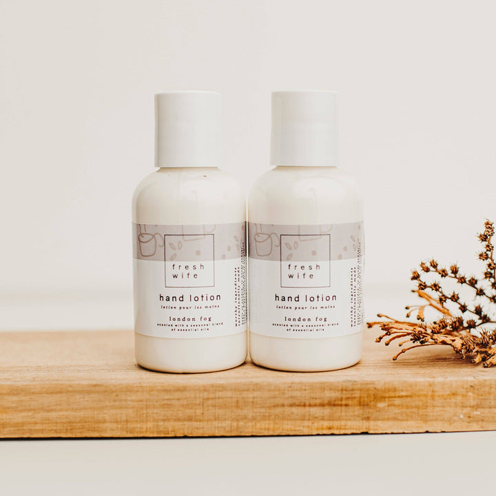 Two bottles of fresh wife hand lotion on a wooden shelf with a minimal background