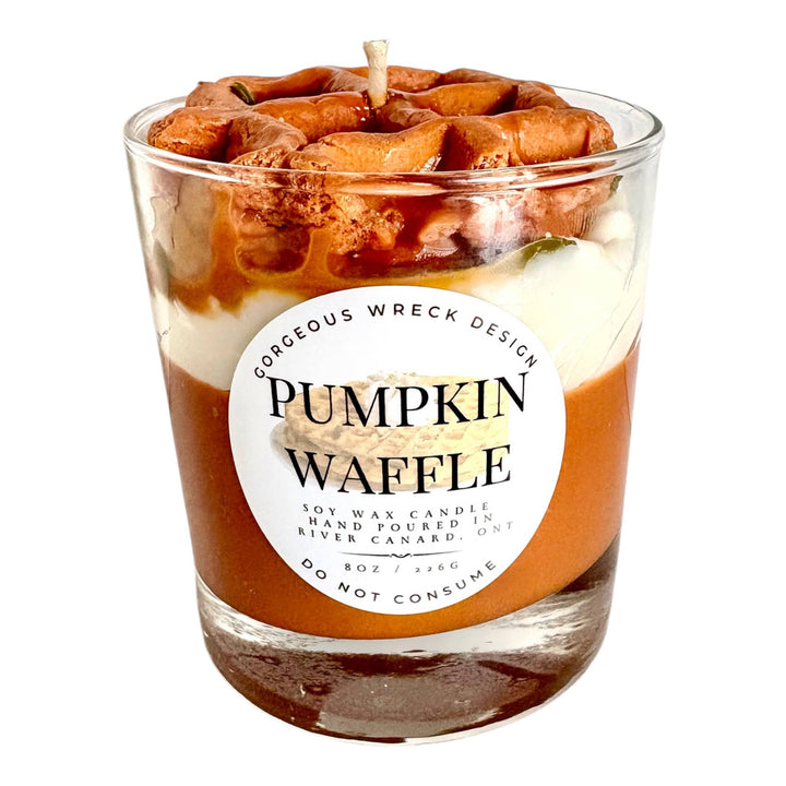 Pumpkin waffle-themed candle with a decorative top in a glass container on a white background.