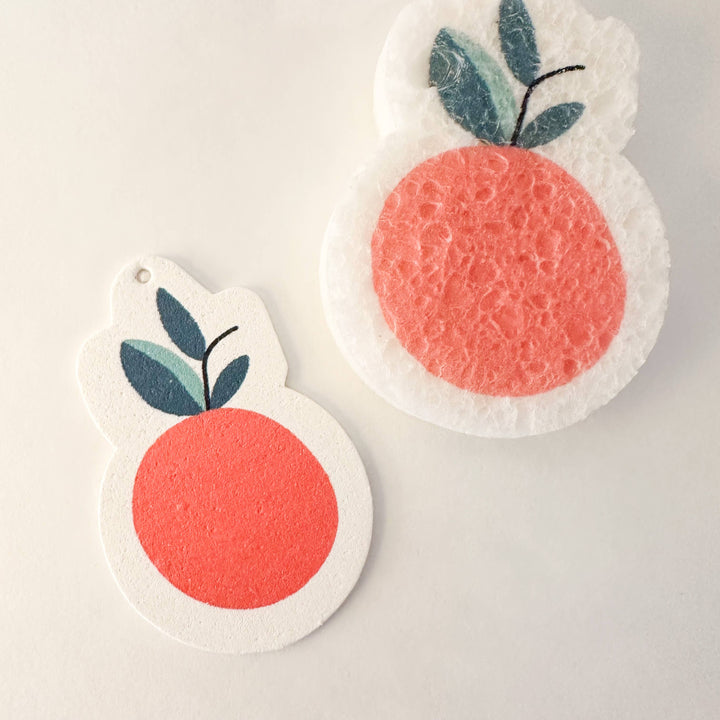 Two peach-shaped sponges with green leaves on a light gray background