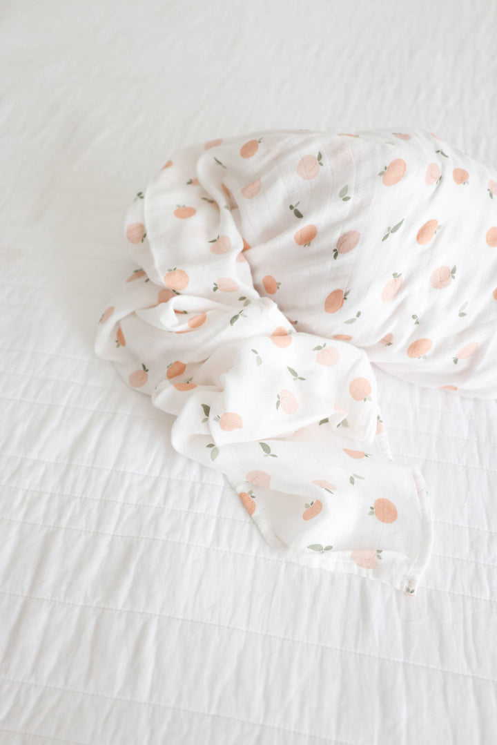 Soft muslin cotton swaddle blanket with peach print for babies by Lulujo Baby, showcasing a gentle, breathable fabric.
