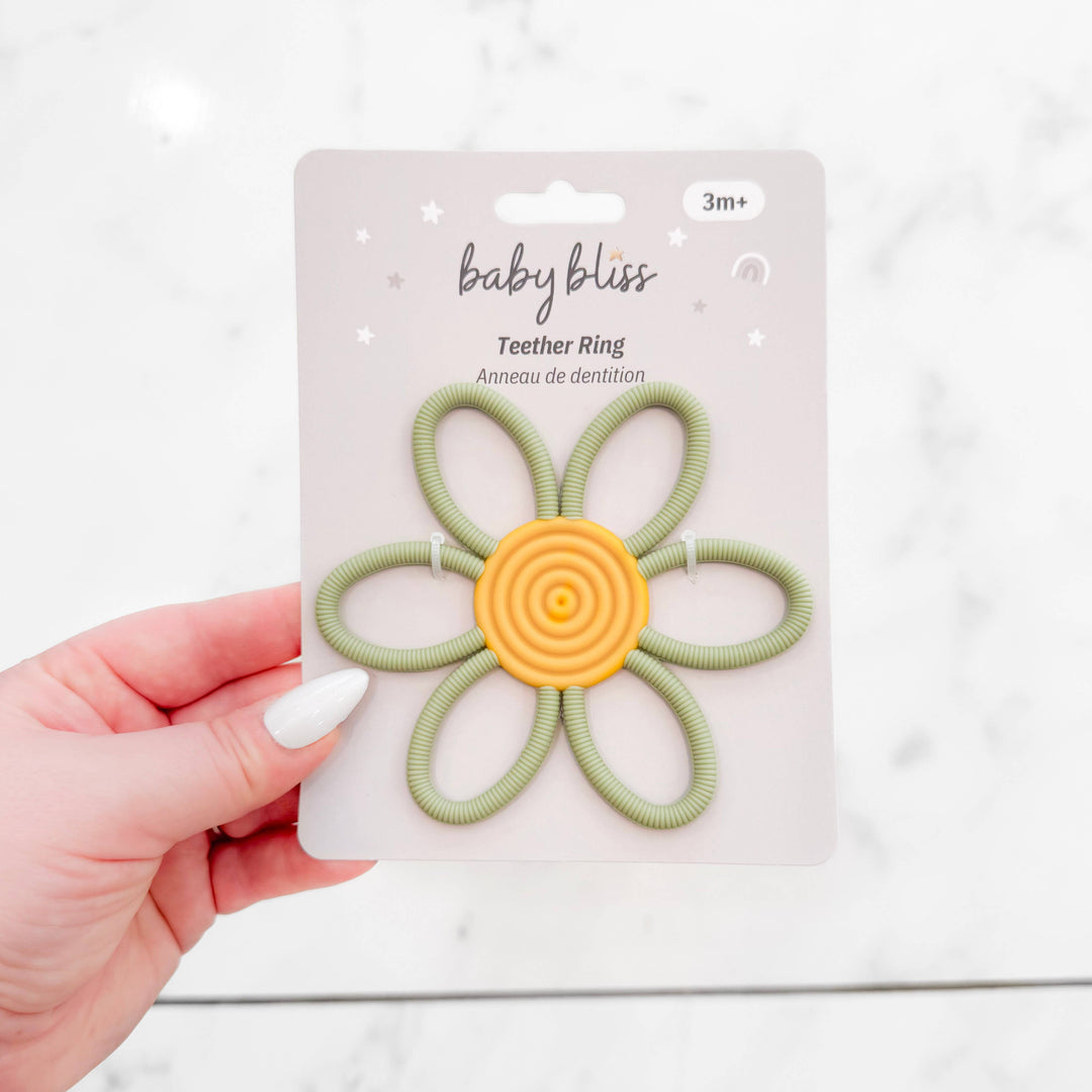 Hand holding a green and yellow teether ring with &