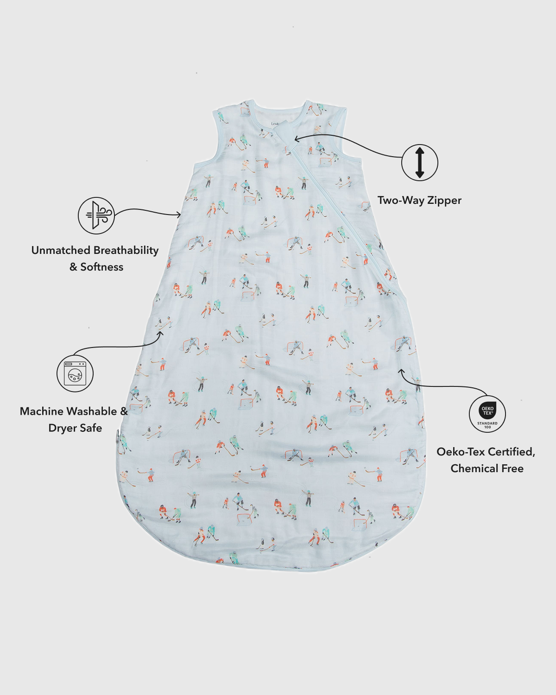 A sleeveless baby sleep sack with a light blue background and a small multicolor winter-themed print, shown on a light gray background with callout lines and icons highlighting features like an unmatched zipper, breathability, washability, and chemical safety.