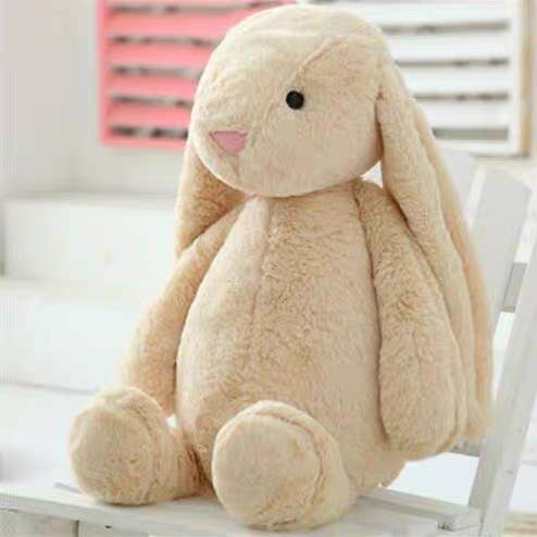 Beige plush bunny toy on a white surface with a blurred background