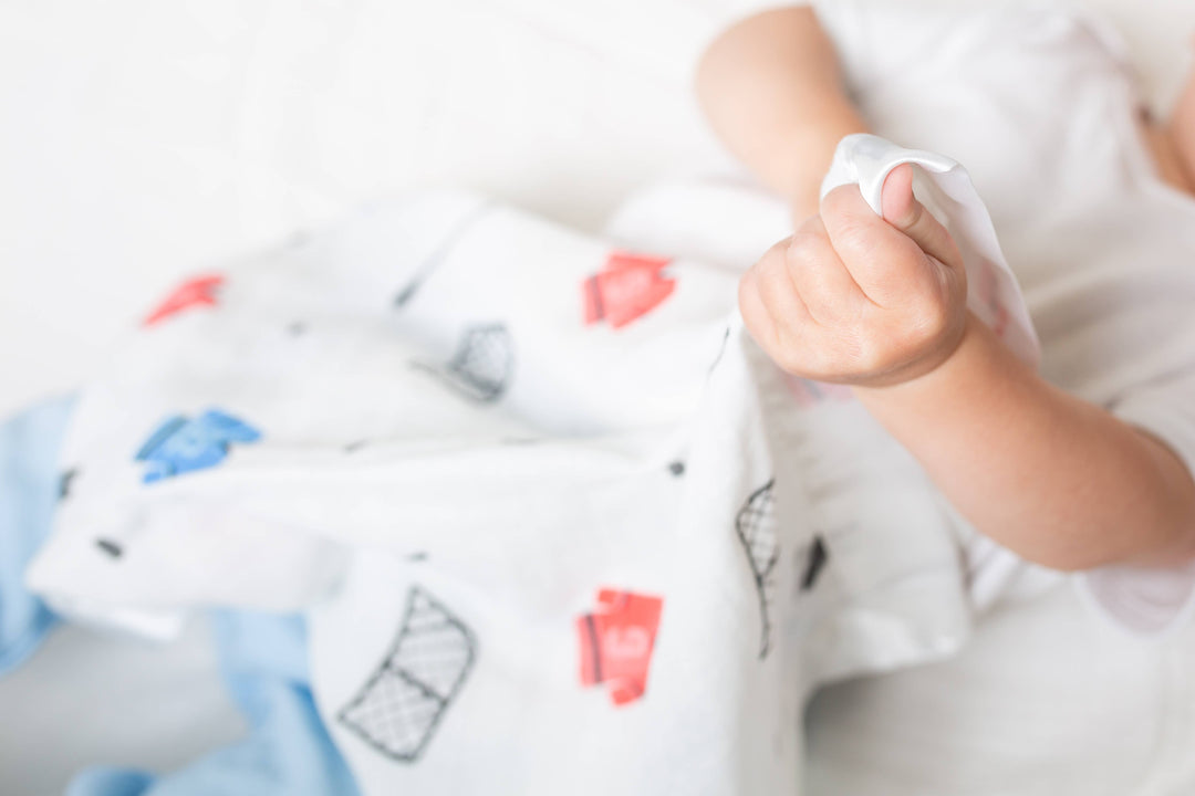 Two Lulujo Baby cotton security blankets featuring hockey-themed designs, soft and cozy for infants.