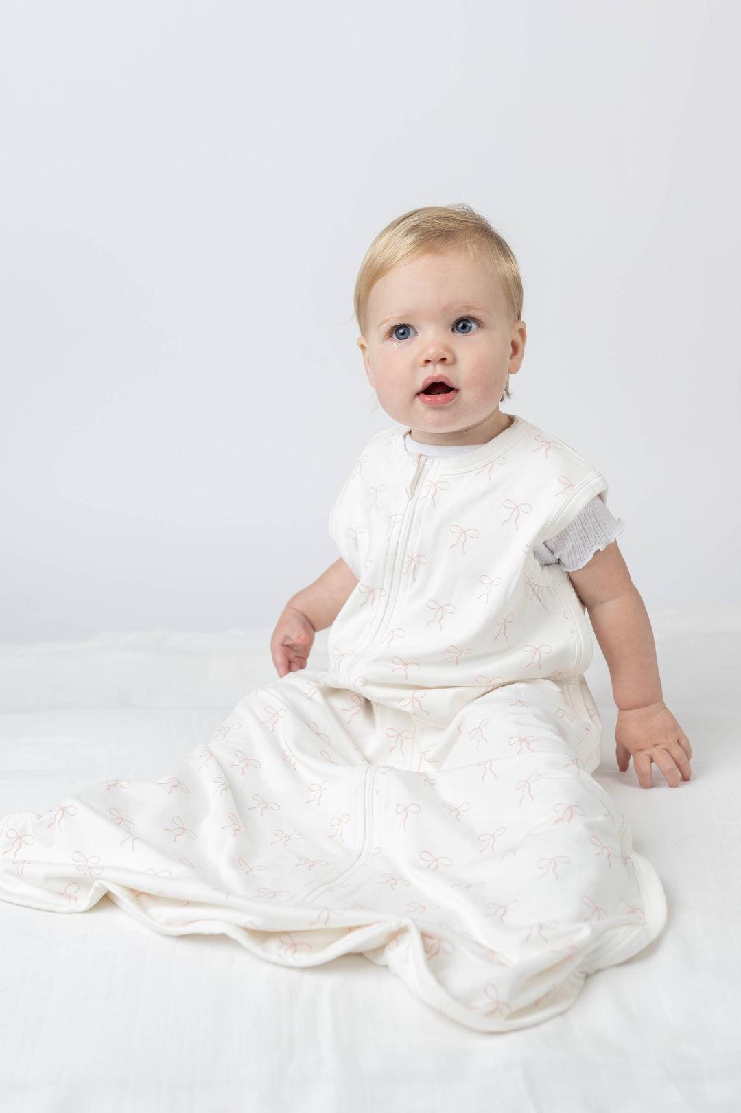 Baby in a white outfit sitting on a white background