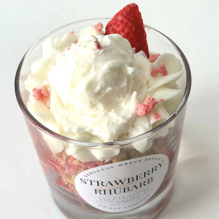 Dessert in a glass with whipped cream, strawberry pieces, and a red strawberry on top.
