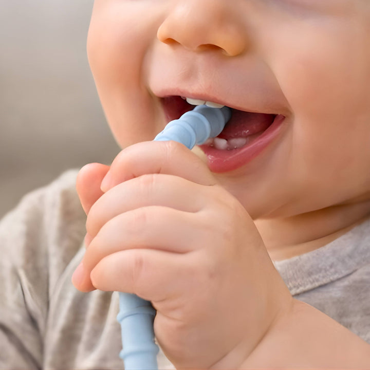 Child brushing their teeth with a blue toothbrush against a neutral background