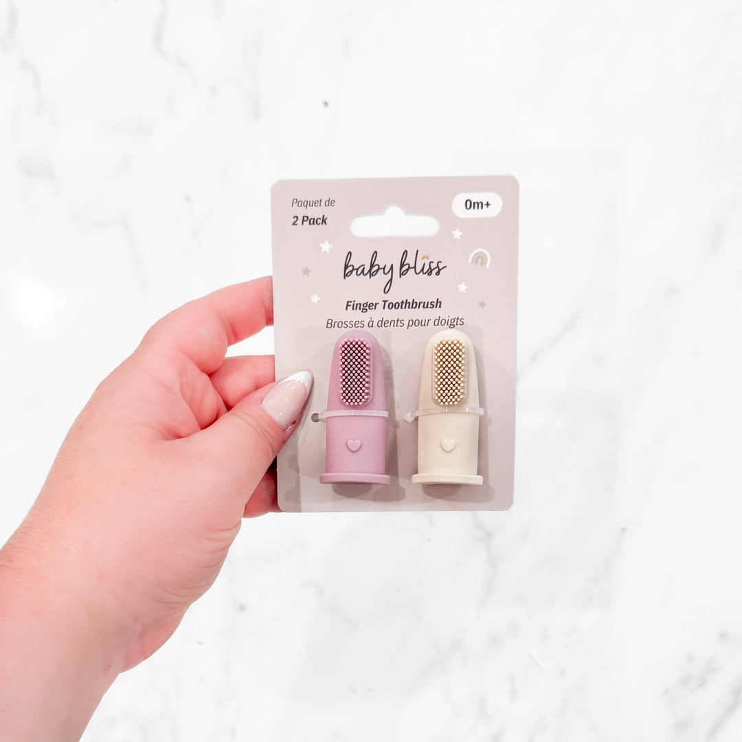 Hand holding a package of baby bliss finger toothbrushes on a white background
