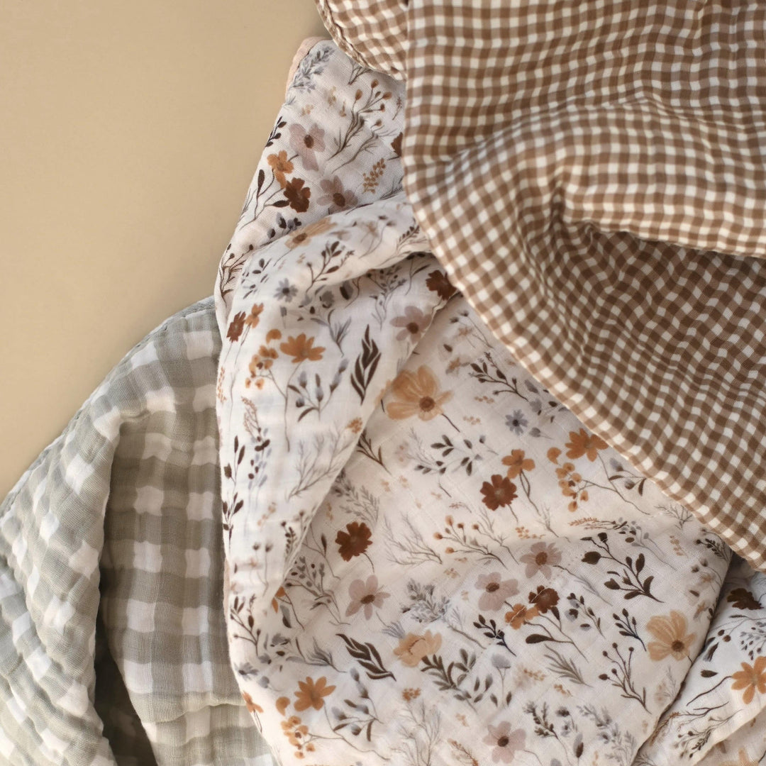 Stack of fabric swatches with floral, checkered, and plain patterns on a beige background