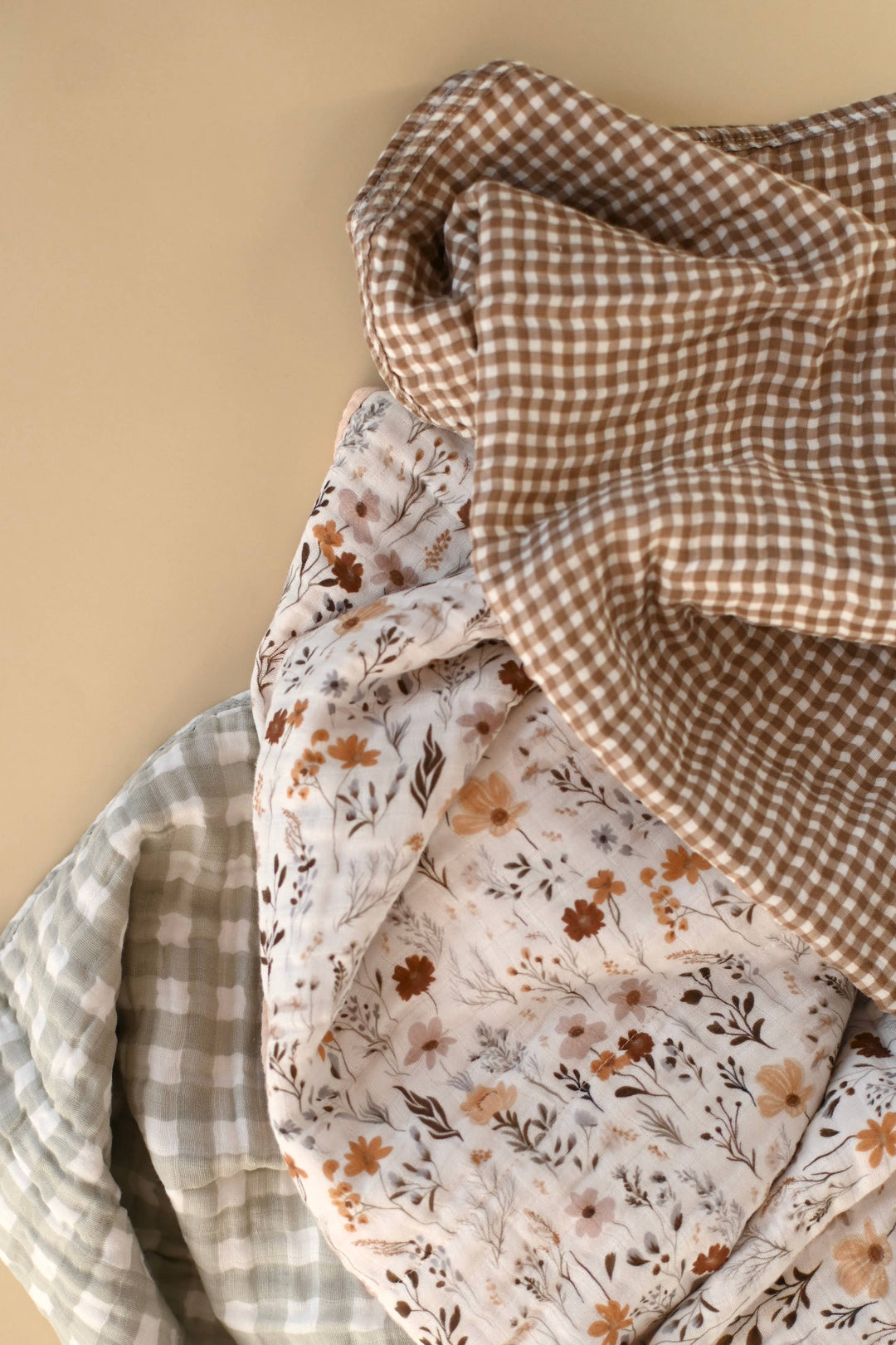 Stack of fabric swatches with floral, checkered, and plain patterns on a beige background