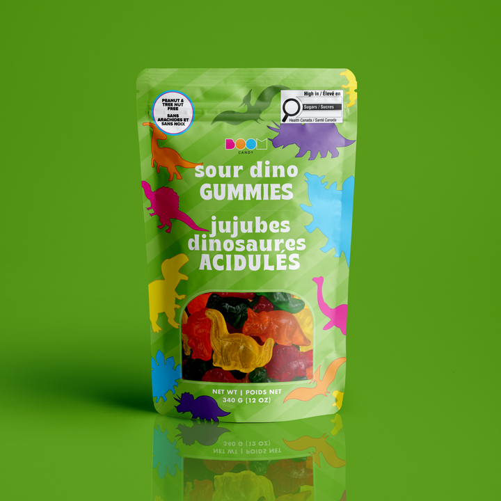 A stand-up pouch of sour dinosaur gummies on a bright green background. The package is light green with colorful dinosaur silhouettes and bilingual text reading &