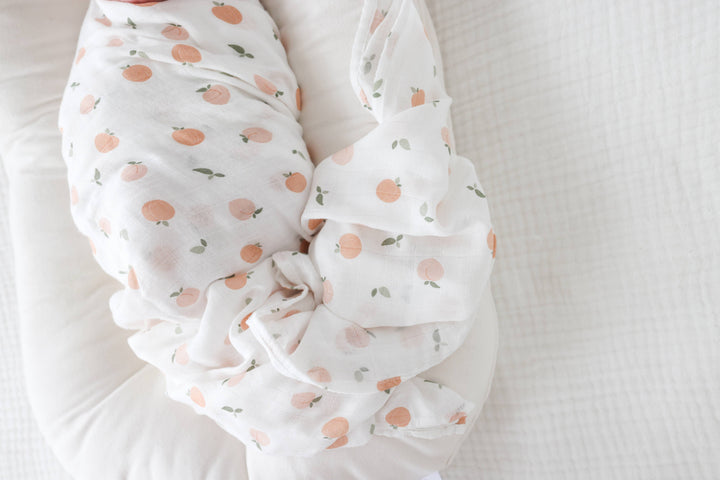 Lulujo Baby muslin cotton swaddle blanket with peach fruit pattern, soft and lightweight for newborns and infants.