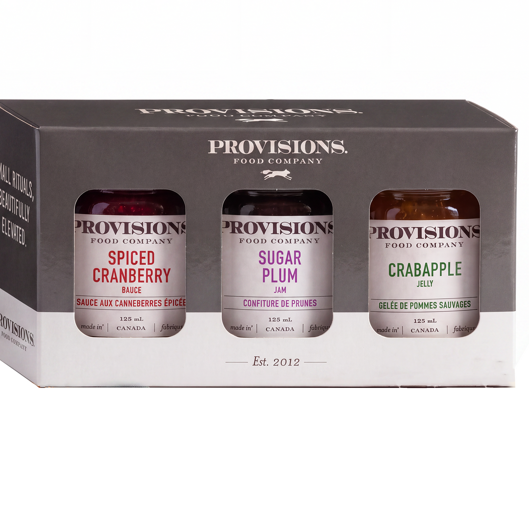 Assorted jars of Provisions Food Company holiday collection jams and jellies with colorful labels and festive packaging.