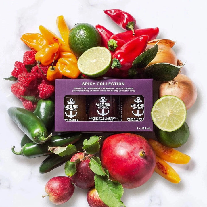 An array of fruits and vegetables surrounding three jars labeled Spicy Collection, with colors predominantly red, yellow, and green.