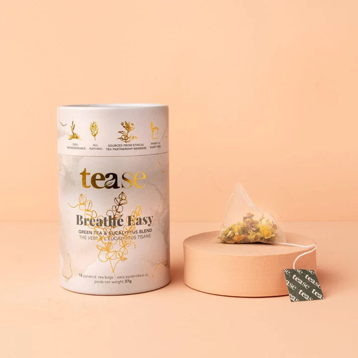A packaged tea product from the brand TEASE, featuring a cylindrical container with a white label, and a single tea bag displayed in front of the package.