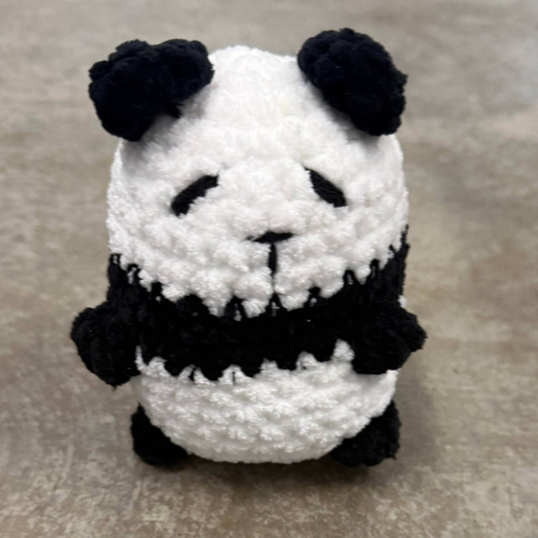 Crocheted panda toy on a gray surface