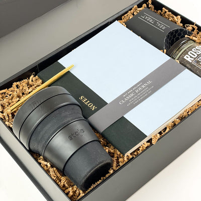 Make work days just a little better with the Desk Essentials Gift Box! Curated for ultimate success, this luxurious gift box has everything needed for whatever their day throws at them!  GIFT CONTENTS:  Rosso Creamy Earl Grey Tea Note To Self Journal Stojo Travel Cup Real Treat Cookies (package of 2) Gold Pen 