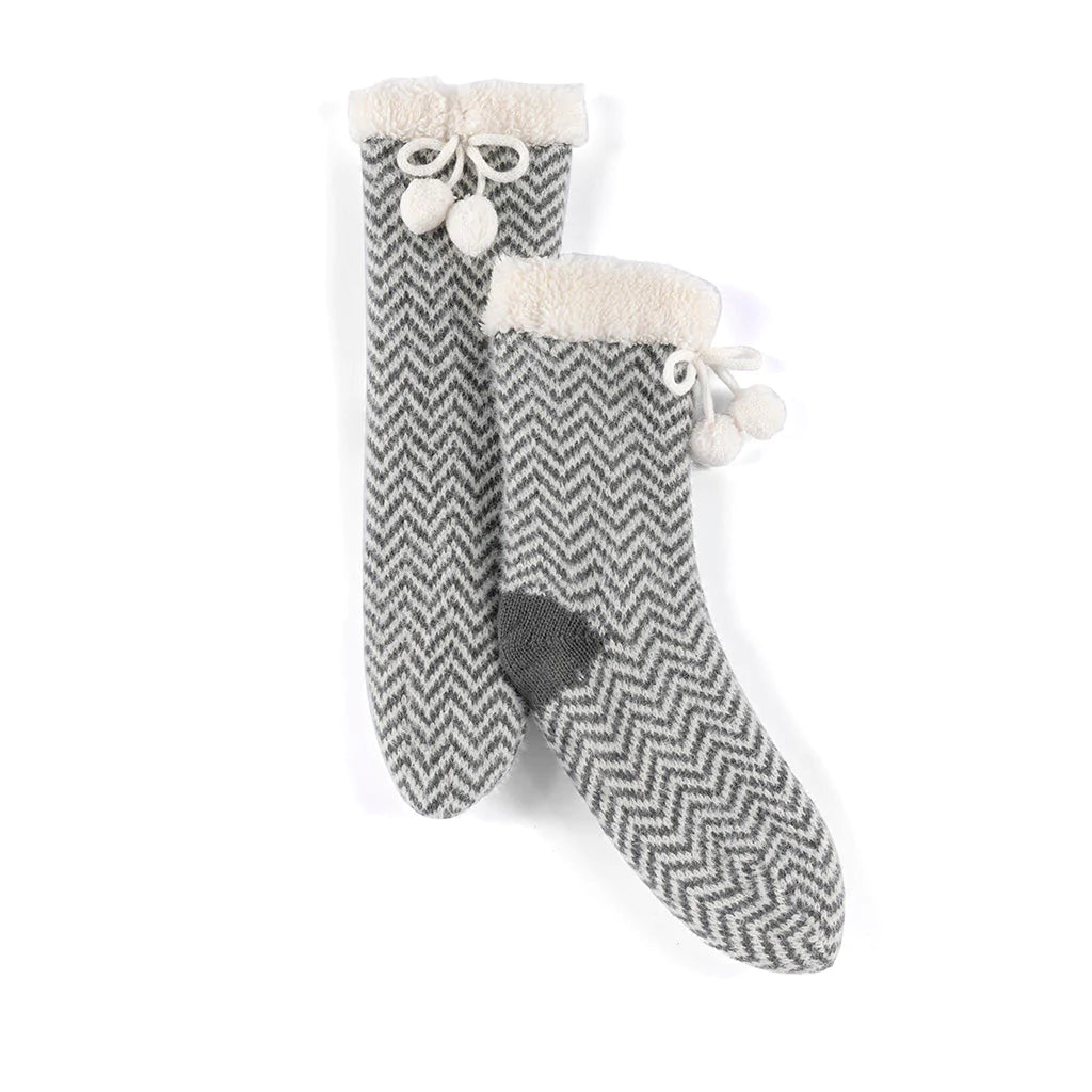 Fuzzy comfort meets polished style in Shiraleah’s Yancy Slipper Socks. These socks feature a knitted texture, with a sherpa lining, a tie with pom pom detailing and have a unique feminine flair. These socks have a rubber grip bottom and are packaged with a belly band making them the perfect gift option.