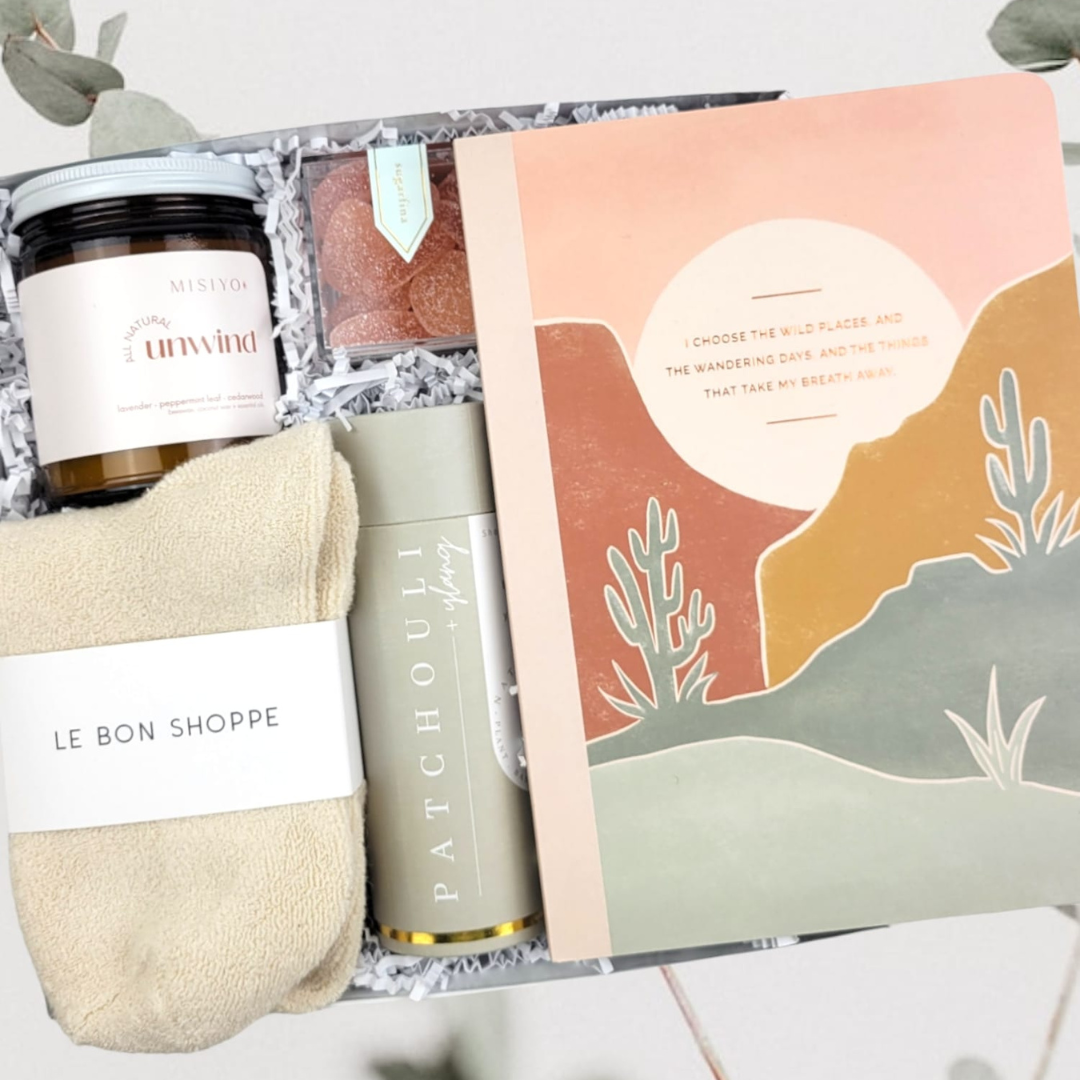 It's time to unwind & relax! We love this collection of luxury self-care items and they will too! Named after the Choose The Wild Places Notebook included for some self-reflection and journaling.   GIFT CONTENTS:  Misiyo Unwind Candle (natural coconut wax naturally scented with lavender, peppermint leaf, & cedarwood) Patchouli Ylang Shower Steamers Le Bonne Shoppe Cloud Socks Sugarfina Tequila Sours Choose The Wild Places Notebook
